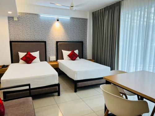a hotel room with two beds and a table at The White Orchid Luxury Service Apartments in Ernakulam