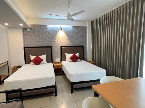a hotel room with two beds and a table at The White Orchid Luxury Service Apartments in Ernakulam