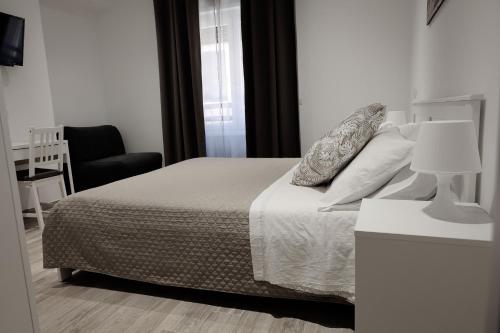a bedroom with a bed with a lamp and a chair at Central Guest House in Civitavecchia
