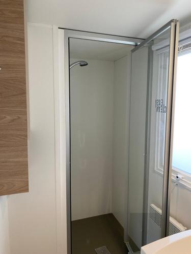 La salle de bains est pourvue d'une douche à l'italienne et d'une porte en verre. dans l'établissement Mobilhome camping le MAR ESTANG, à Canet