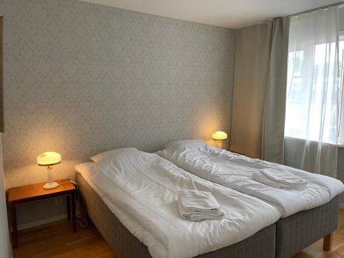 a bed in a bedroom with two lamps and a window at Vadstena centrum in Vadstena