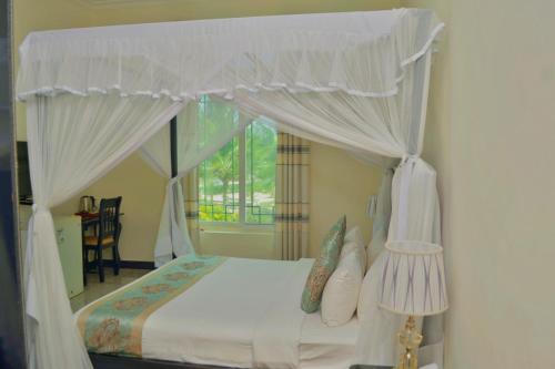ein Schlafzimmer mit einem Himmelbett und einem Fenster in der Unterkunft Royal Cliff Zanzibar in Zanzibar City