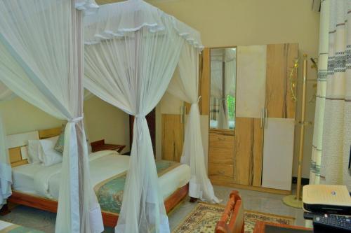 a bedroom with a canopy bed and a shower at Royal Cliff Zanzibar in Zanzibar City