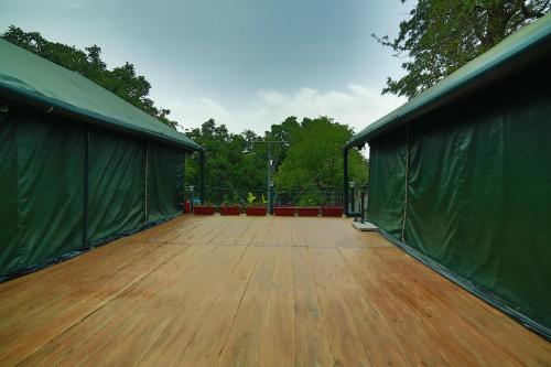 a large deck with a wooden floor and green walls at The Colonial Manek Manor By SAH in Mount Ābu