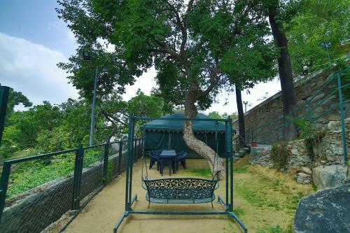 a garden with a table and a tree in a cage at The Colonial Manek Manor By SAH in Mount Ābu