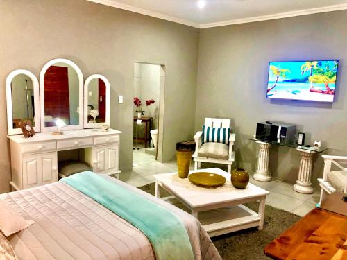 a bedroom with a bed and a bathroom with a tv at Rooibos Retreat in Richards Bay