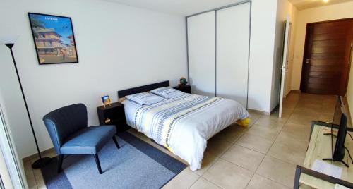 a bedroom with a bed and a blue chair at Studio confort avec jardinet in Montjoly