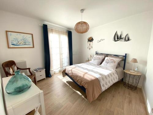 a bedroom with a bed and a table and a window at Ty Gavrinis - T2- Centre Bourg - 100m de la mer in Larmor-Baden