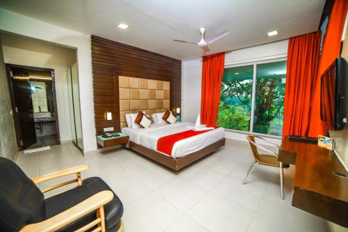 a bedroom with a bed and a couch and a television at Grand Palace Hotel & Spa in Yercaud