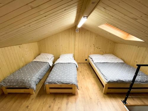 two beds in a room with wooden walls at Beskidzka Stodoła in Żywiec