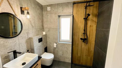 een badkamer met een wastafel, een toilet en een spiegel bij Beskidzka Stodoła in Żywiec