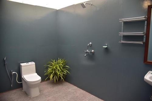 a bathroom with a toilet and a plant in it at Jardim a Mar in Agonda