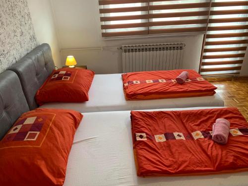 three beds with red pillows in a room at Guest House Husejn in Dubrave Gornje