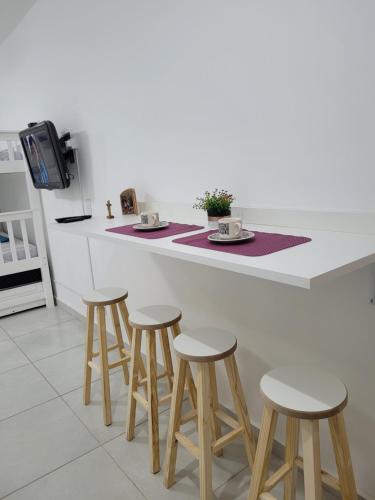 une cuisine avec un comptoir avec quatre tabourets et un comptoir dans l'établissement Apartamento Canção Nova, à Cachoeira Paulista