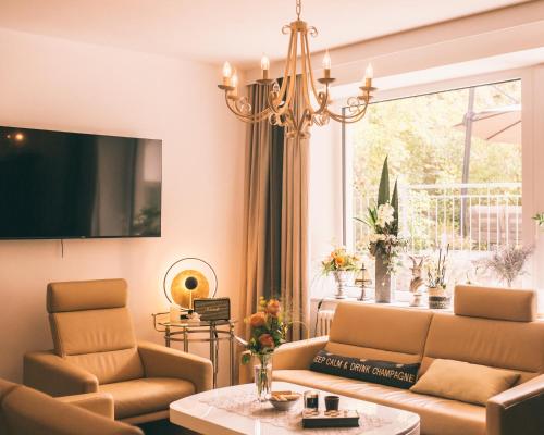 uma sala de estar com um sofá e cadeiras e uma televisão em Nefer, Haus em Bad Gastein