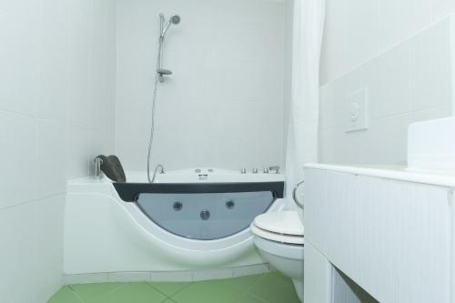a white bathroom with a bath tub next to a toilet at Budapest Bed and Breakfast in Budapest