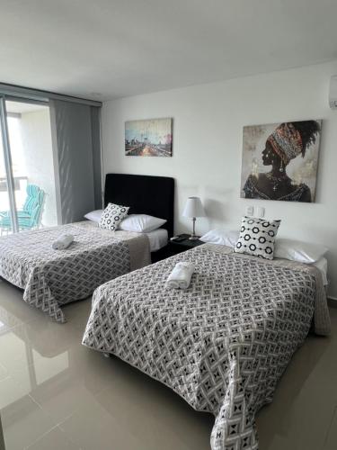Duas camas num quarto com paredes brancas em Sunny House em Cartagena das Índias