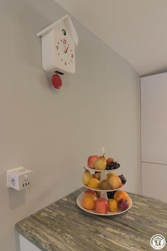 a plate of fruit on a counter with a clock at Villa "La Recrée Toulousaine " Clim & SPA-12 couchages in Cugnaux