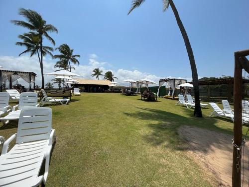a group of white chairs and umbrellas on the grass at Apartamento standart premium aconchegante in Subaúma