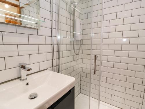 a white bathroom with a sink and a shower at Ty Taid in Gaerwen