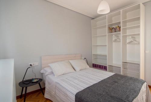 a bedroom with a bed with white walls and shelves at la casa de los lapiceros in Talavera de la Reina