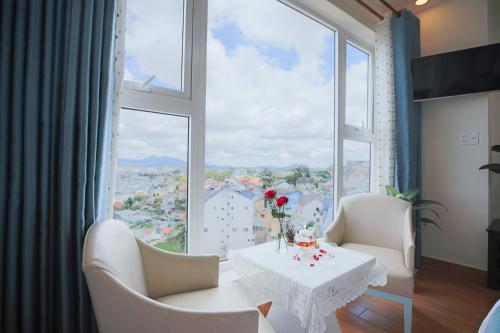 een kamer met een tafel en stoelen en een groot raam bij Rose Valley Hotel Da Lat Vietnam in Da Lat