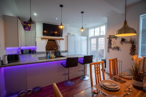 a kitchen with purple lighting and a table and chairs at Cavendish Cat and Gaming House in Blackpool