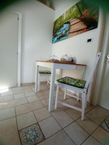 a table and a chair in a room with a painting at La loggetta 63 in Palagianello