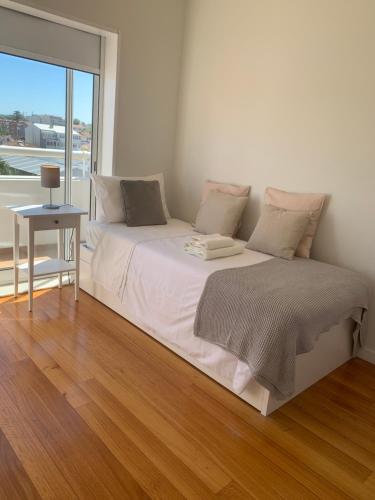 Cama blanca en habitación con ventana grande en Sunset Guest House, en Matosinhos