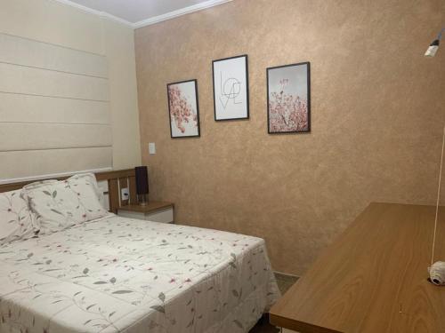 a bedroom with a bed and four pictures on the wall at Apartamento Novissimo Aquarius II in Poços de Caldas