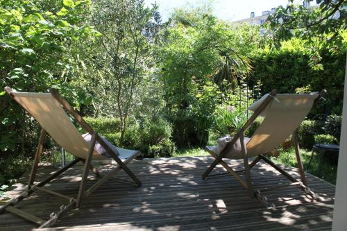 two chairs sitting on a deck in a garden at chambre indépendante sur jardin avec SDE et cuisine in Nantes