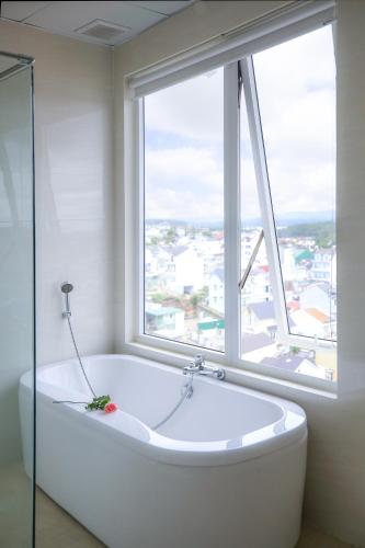 a bath tub in a bathroom with a large window at Rose Valley Hotel Da Lat Vietnam in Da Lat