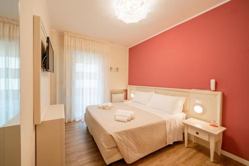 1 dormitorio con cama y pared roja en Hotel Orchidea, en Cervia