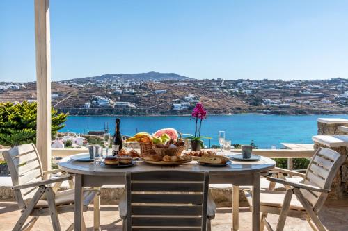 Yalos Mykonos Ornos Pouli private apartments w shared swimming pool في مدينة ميكونوس: طاولة طعام وإطلالة على المحيط