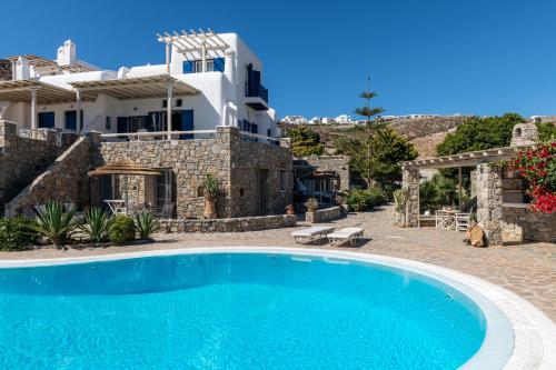 eine Villa mit einem Pool und einem Haus in der Unterkunft Yalos Mykonos Ornos Pouli private apartments w shared swimming pool in Mykonos Stadt