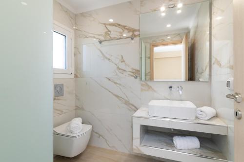 Spartakos Luxury Villa 4 في بلانوس: حمام أبيض مع حوض ومرآة