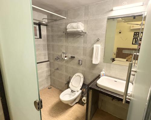 a bathroom with a toilet and a sink and a mirror at Royal Palms Luxury Service Apartment in Nagpur