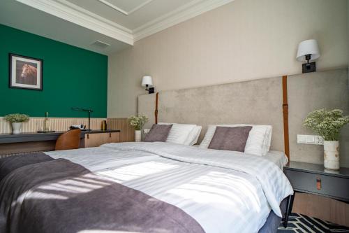 a bedroom with a large bed with a green wall at Santa Natura Resort & SPA in Nowa Wieś