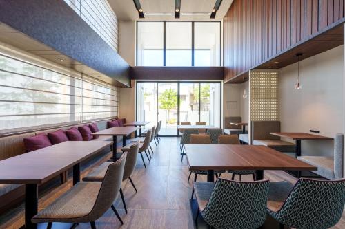 a restaurant with wooden tables and chairs and windows at Hotel GrandConsort Naha in Naha