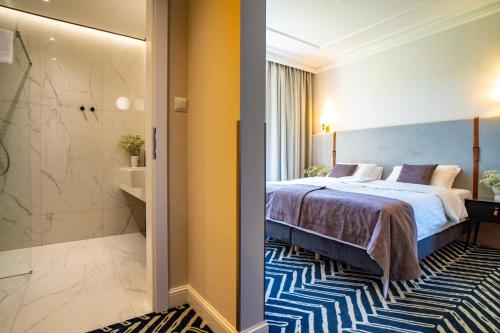 a hotel room with a bed and a bathroom at Santa Natura Resort & SPA in Nowa Wieś