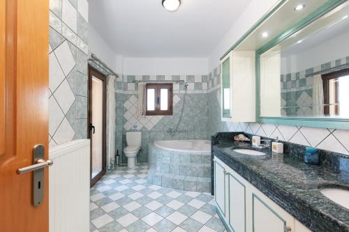 uma casa de banho com 2 lavatórios, uma banheira e um WC. em Villa Sevdas em Perama