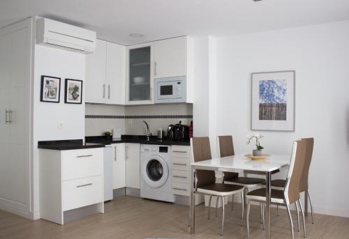 a kitchen with white cabinets and a table and chairs at CENTRO PICACHO in Málaga