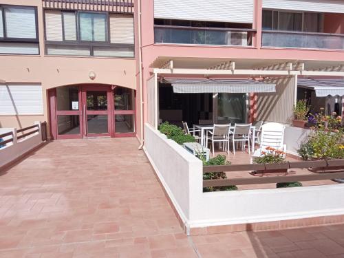 eine Terrasse außerhalb eines Gebäudes mit einem Tisch und Stühlen in der Unterkunft Residence Saint Clair - Studio Elena in Cap d'Agde
