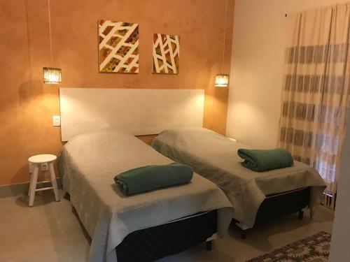 1 dormitorio con 2 camas con almohadas verdes en Suites Terrasol, en Ilhabela