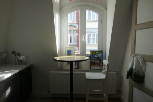 une table et une chaise dans une chambre avec fenêtre dans l'établissement Appartement - Villa Léopold à Malo, à Dunkerque