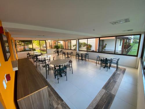 una cafetería vacía con mesas, sillas y ventanas en Apartamento Cobertura Paraíso das Águas - GUARAJUBA, en Camaçari