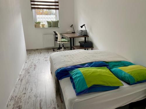 Un dormitorio con una cama con almohadas de colores y un escritorio. en Residence Park lovely apartman with private parking, en Kysucké Nové Mesto