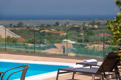 a pool with two chairs and a view of a resort at Sea n' Smile in Apolpaina