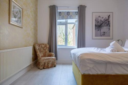 a bedroom with a bed and a chair and a window at Spacious 5 Bedroom House in Birmingham close to NEC For 12 Guests in Birmingham
