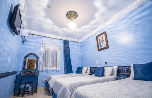 a blue room with two beds and a mirror at Hotel Tarek in Chefchaouen